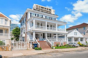 A multi-story residential building with a front porch, a staircase, and a gated entrance. - 4 BR | Getaway w/ Beach Access & BBQ (Atlantic City)