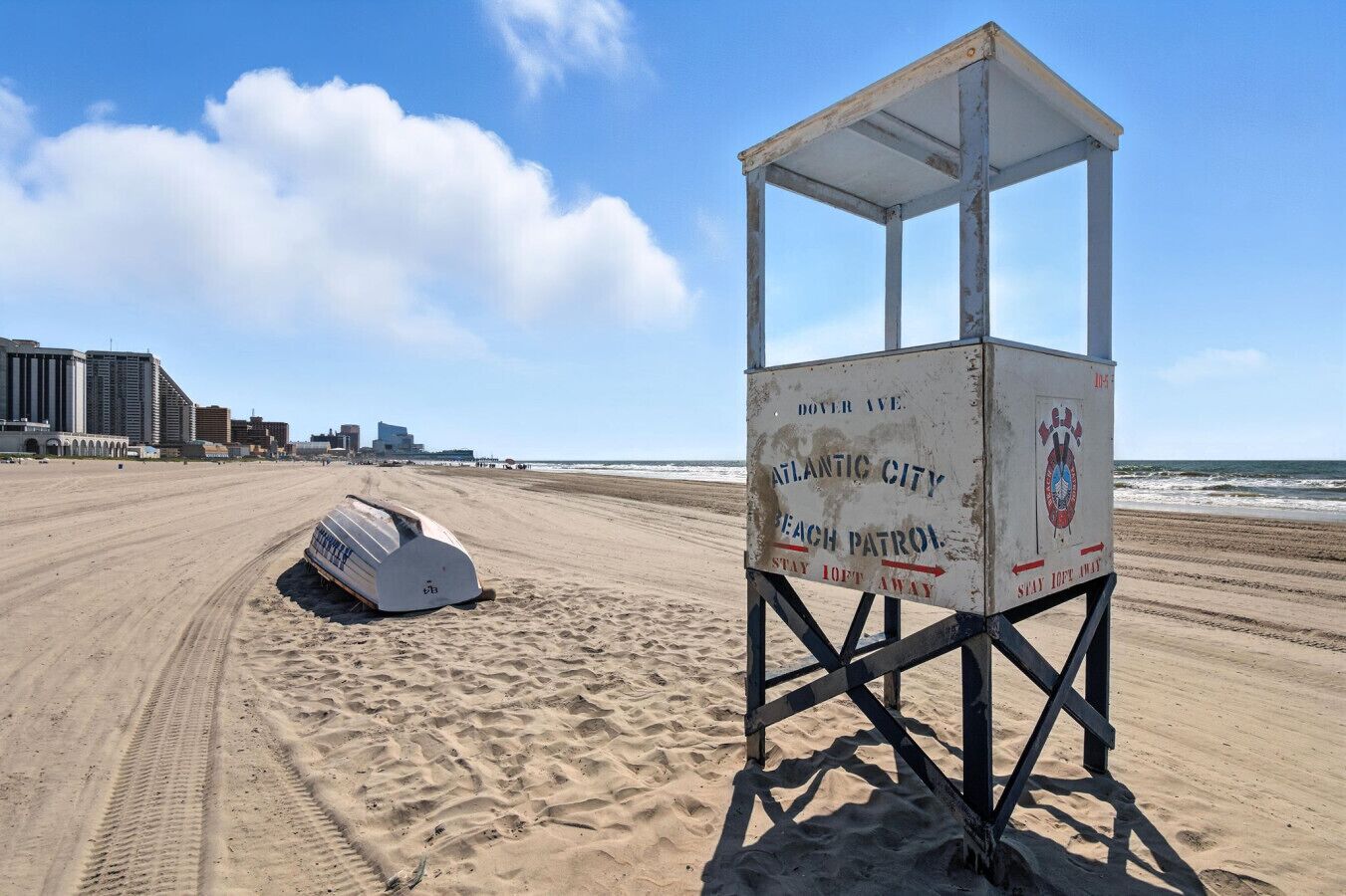 A lifeguard tower on a beach with a boat lying on the sand nearby.