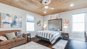 Une chambre à coucher comprenant un lit, un canapé, un bureau et des œuvres d’art accrochées aux murs.