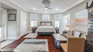 Une chambre à coucher comprenant un lit, un bureau, une chaise, une commode et un ventilateur de plafond.