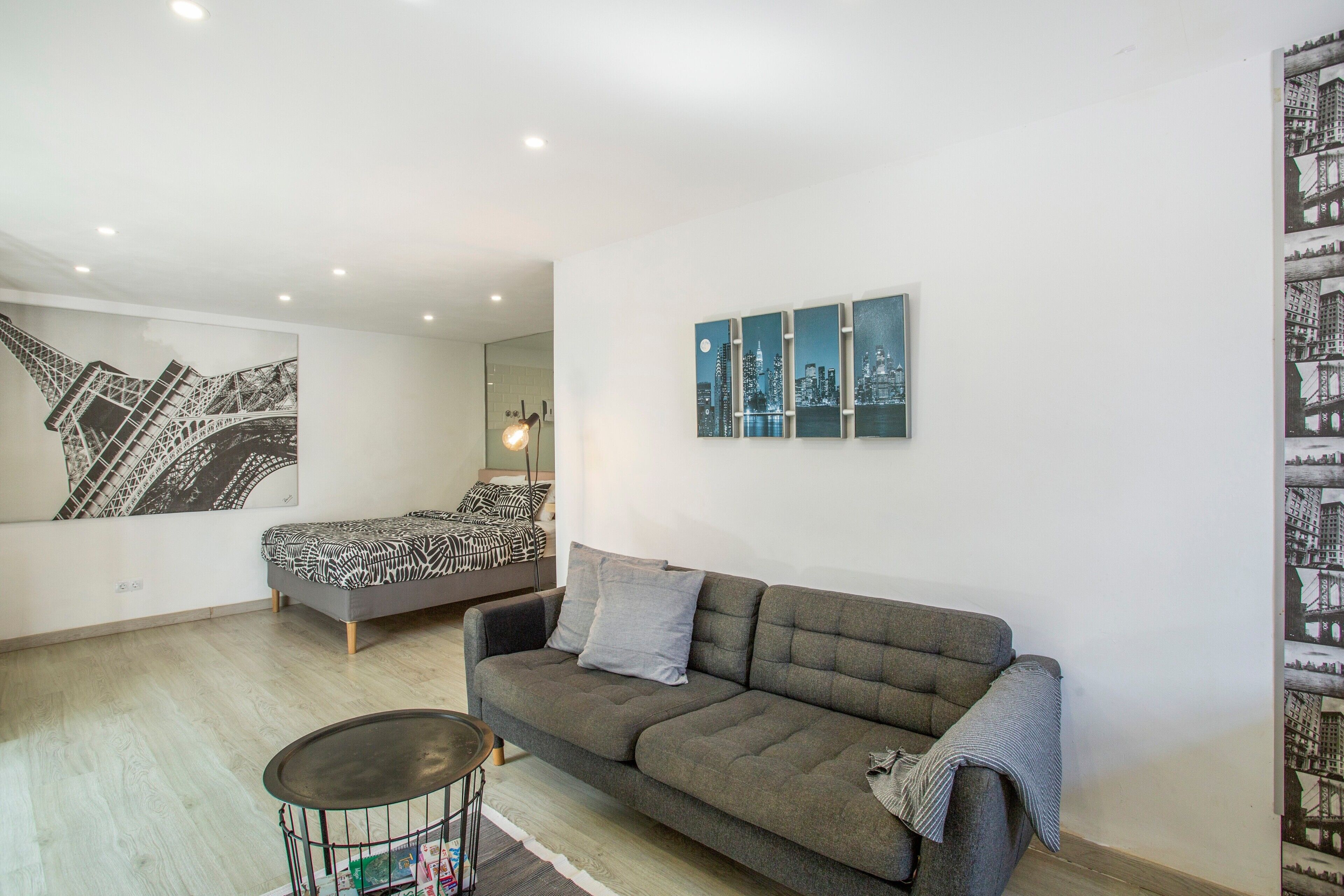 Un salon moderne avec un canapé, une petite table et un lit agrémenté de linge de lit à motifs.