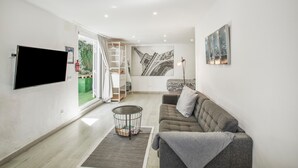 A modern living room with a flat-screen TV, a grey sofa, a round coffee table, and a staircase leading to an outdoor area. - Vacation Home 'Ita' with Private Terrace, Wi-Fi and Air Conditioning (Mogán)