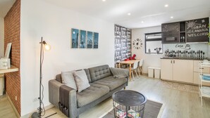 A modern living room with a sofa, a dining table, and a kitchen area with a refrigerator and cabinets. - Vacation Home 'Ita' with Private Terrace, Wi-Fi and Air Conditioning (Mogán)