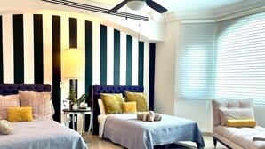 Une chambre avec deux lits, une table de chevet, une chaise et un ventilateur de plafond.