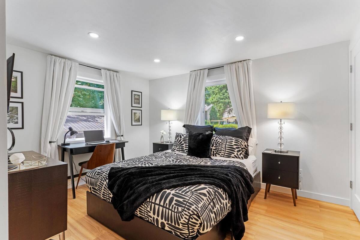 A bedroom with a bed, desk, chair, and nightstands.