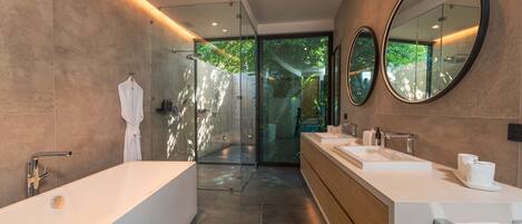 A modern bathroom with a large bathtub, two sinks, and a glass shower enclosure.