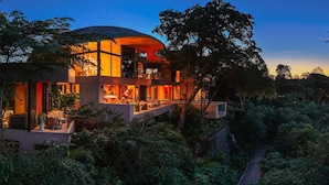 Ein modernes Haus mit gewölbter Dachform, großen Fenstern und einem Garten.