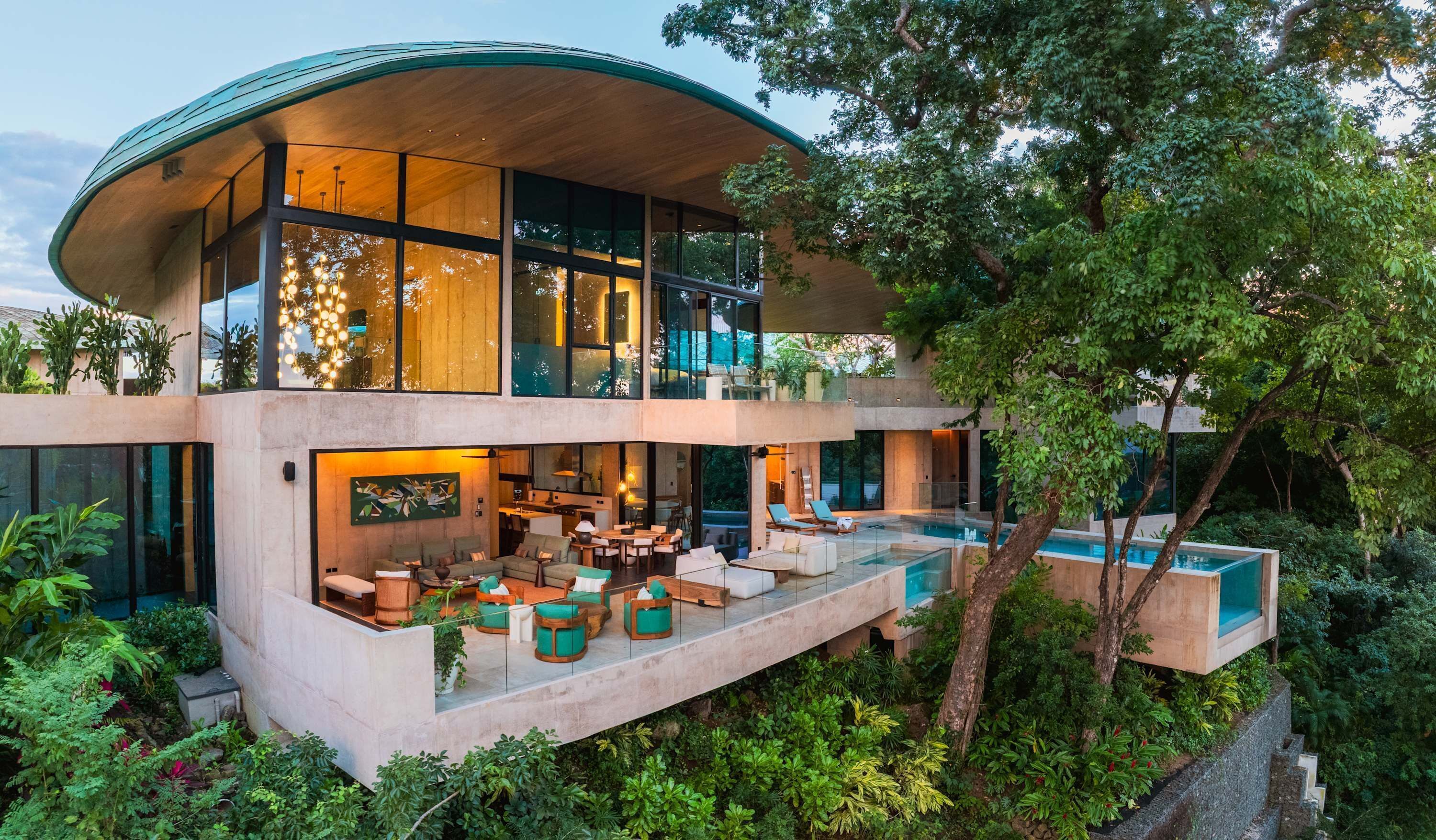 Una casa moderna de dos pisos con techo curvo, amplios ventanales y una piscina.