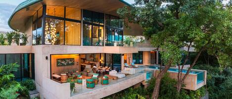 Una casa moderna de dos pisos con techo curvo, amplios ventanales y una piscina.