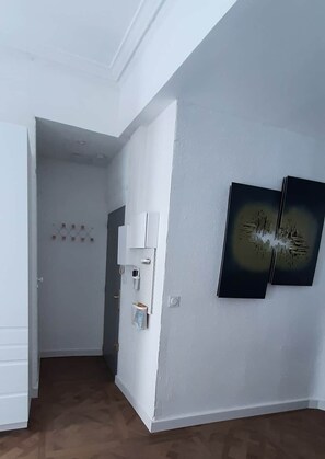Ein Zimmer mit weißer Wand, einer Tür, einem Lichtschalter und einer Steckdose.