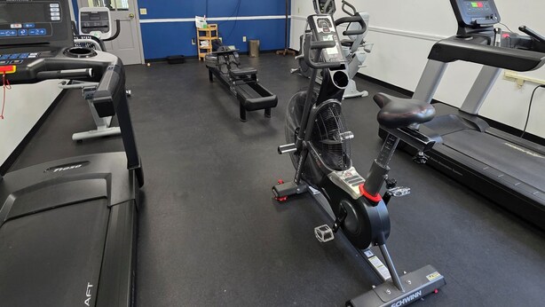 A gym with treadmills, stationary bikes, and a wall-mounted TV. - Cozy 1-bedroom lodging in Westfield's Historic YWCA -Queen size bed (Westfield)