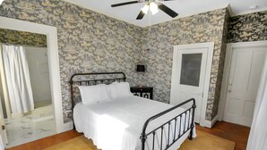 A bedroom with a bed, a ceiling fan, a nightstand, a door, and a shower area. - Cozy 1-bedroom lodging in Westfield's Historic YWCA -Queen size bed (Westfield)
