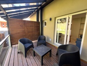 A balcony with wicker furniture, a small table, and a sliding glass door leading to an indoor area.