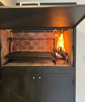 A wood-fired oven with a brick interior and metal shelves.