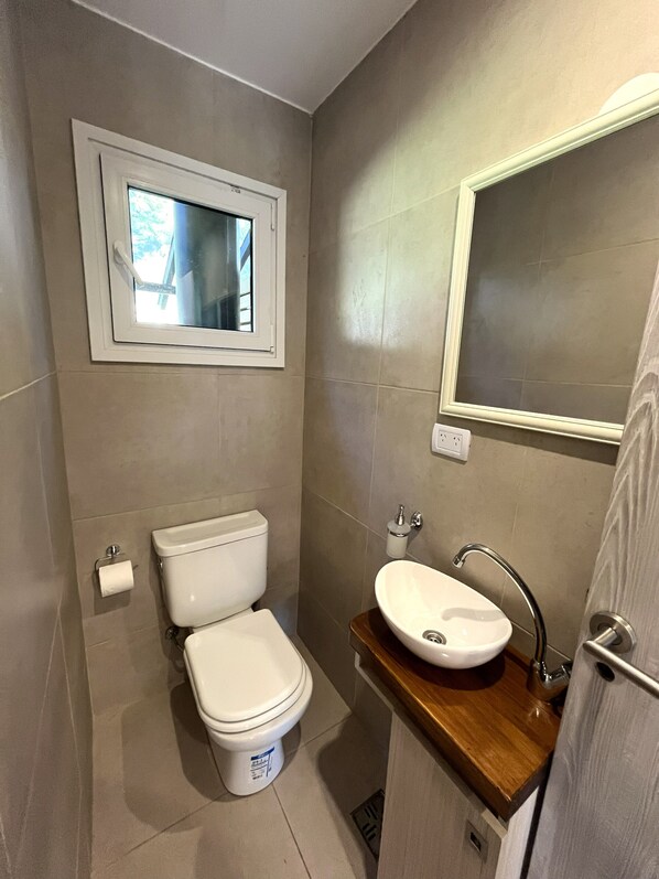 A compact bathroom with a toilet, sink, and window.