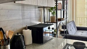 Een moderne keuken met een ingebouwde kookplaat, een zwarte koffieapparaat en een aanrecht met een kom en een bord.