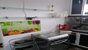 Una cocina con estufa a gas, microondas y salpicadero de azulejos con motivos de frutas.