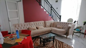 A living room with a sectional sofa, a glass coffee table, and a patterned rug. - Full Furnished Charming Home (Negombo)