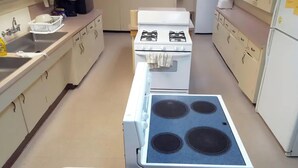 A kitchen with a stove, sink, and refrigerator.
