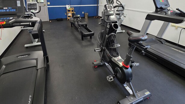 A gym with treadmills, stationary bikes, and a wall-mounted TV.