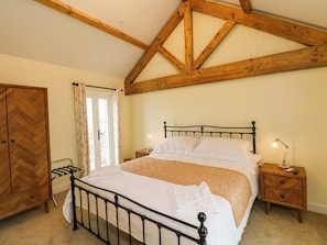 Ein Schlafzimmer mit einem Bett, Nachttischen, einem Holzschrank und einem Fenster mit Vorhängen.