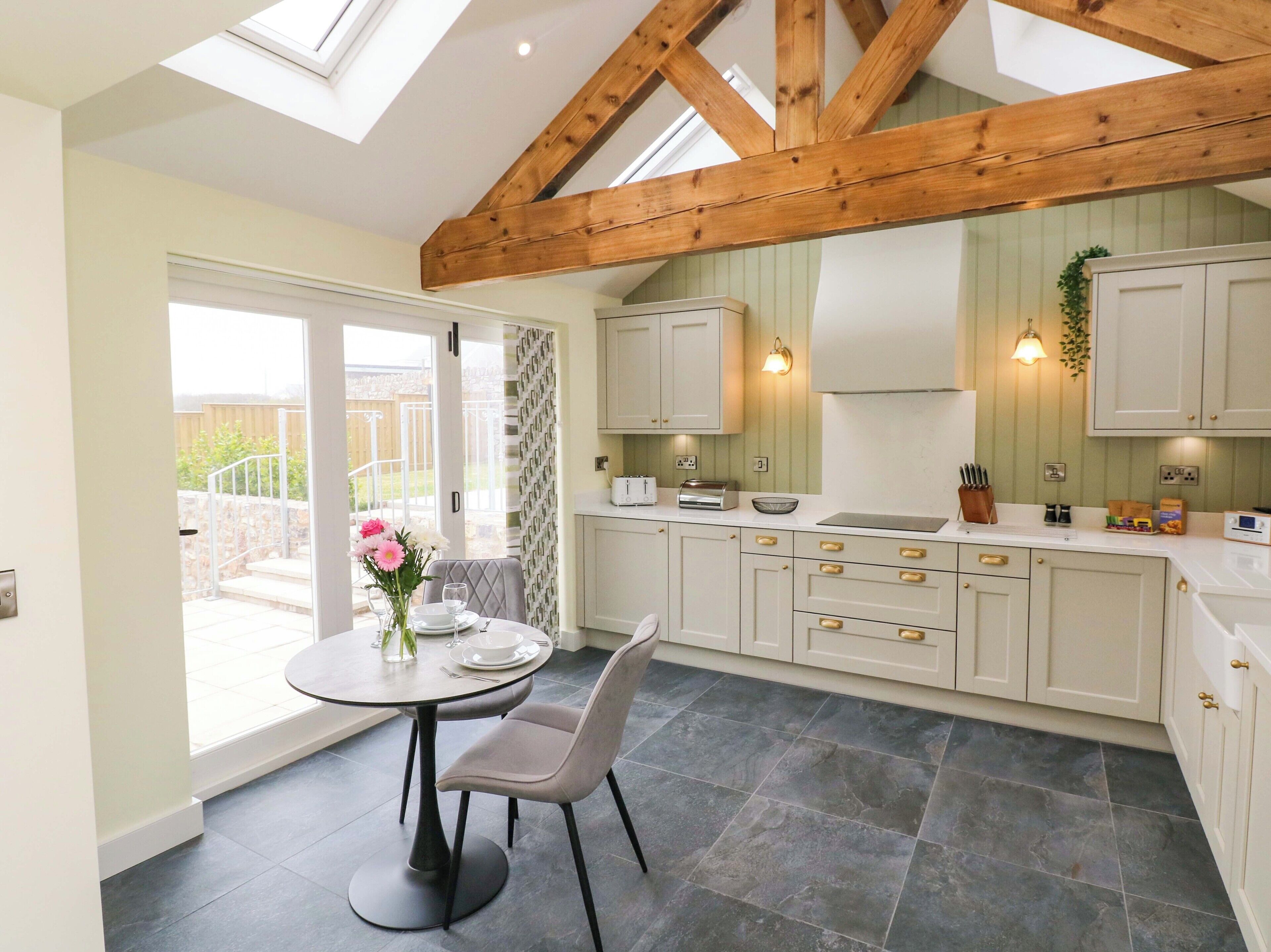 A kitchen with a dining area, featuring a table with chairs, a window, and a view of the outside.