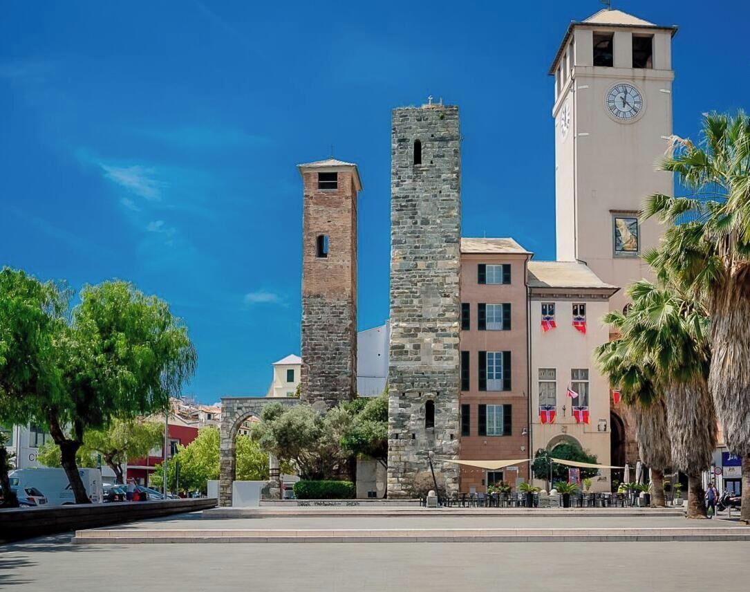 Un bâtiment historique doté d’une tour horloge, d’une haute tour en pierre et d’un autre bâtiment avec une horloge.