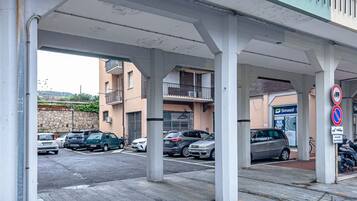 A parking area with cars, a gas station, and a no parking sign.