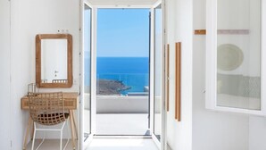 A room with a wooden desk, a chair, a mirror, and a view of the sea through a glass door. - MZ Deep Blue (Kithnos)