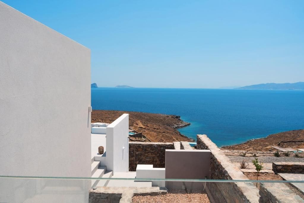 A modern building with a glass balcony overlooking a coastal landscape.