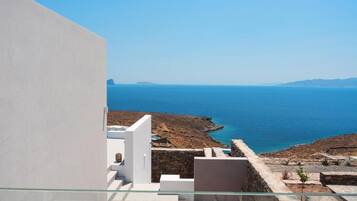 A modern building with a glass balcony overlooking a coastal landscape.