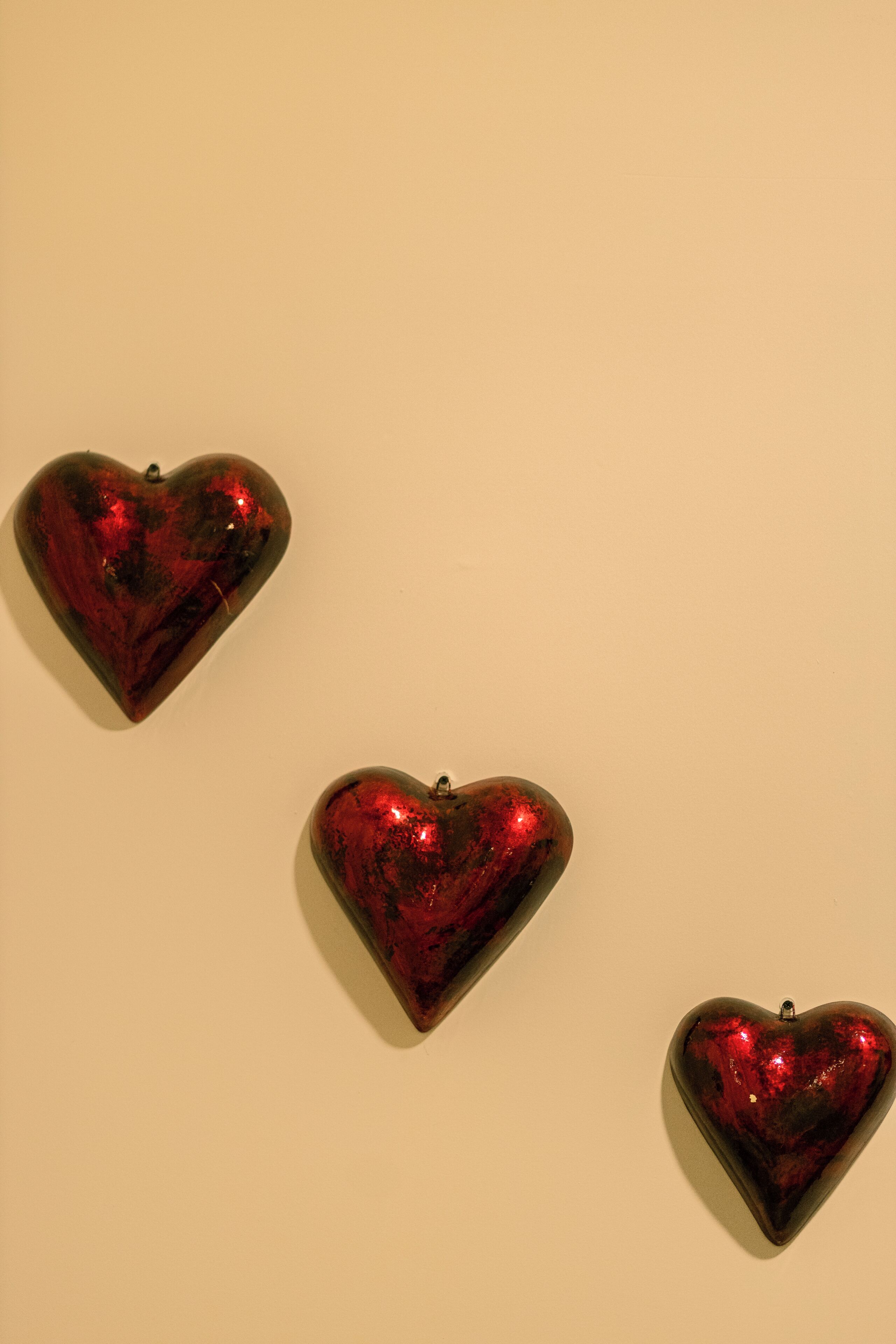 Tres objetos con forma de corazón sobre una pared lisa.