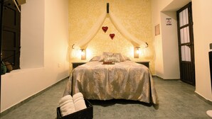 Habitación de hotel con cama, dos lámparas de noche, un reloj en la pared y una puerta con ventanal.