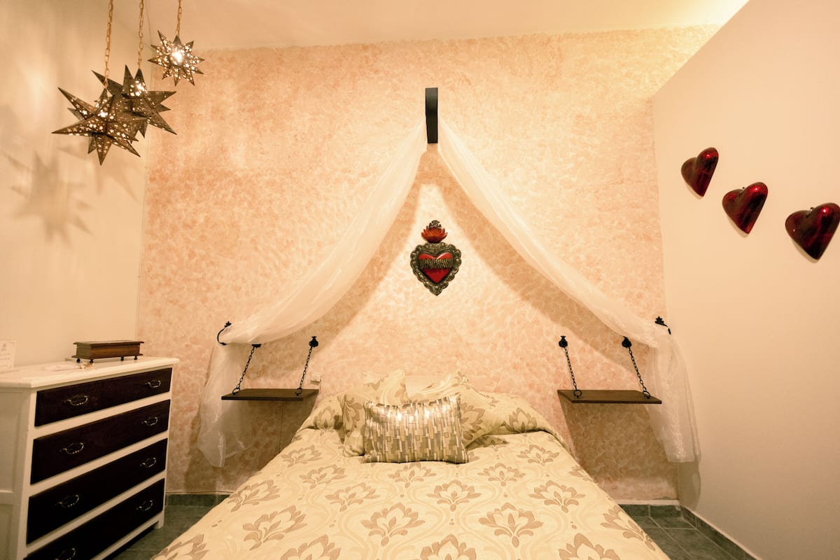 A bedroom with a bed, a dresser, a decorative star, a heart-shaped ornament, and a canopy.