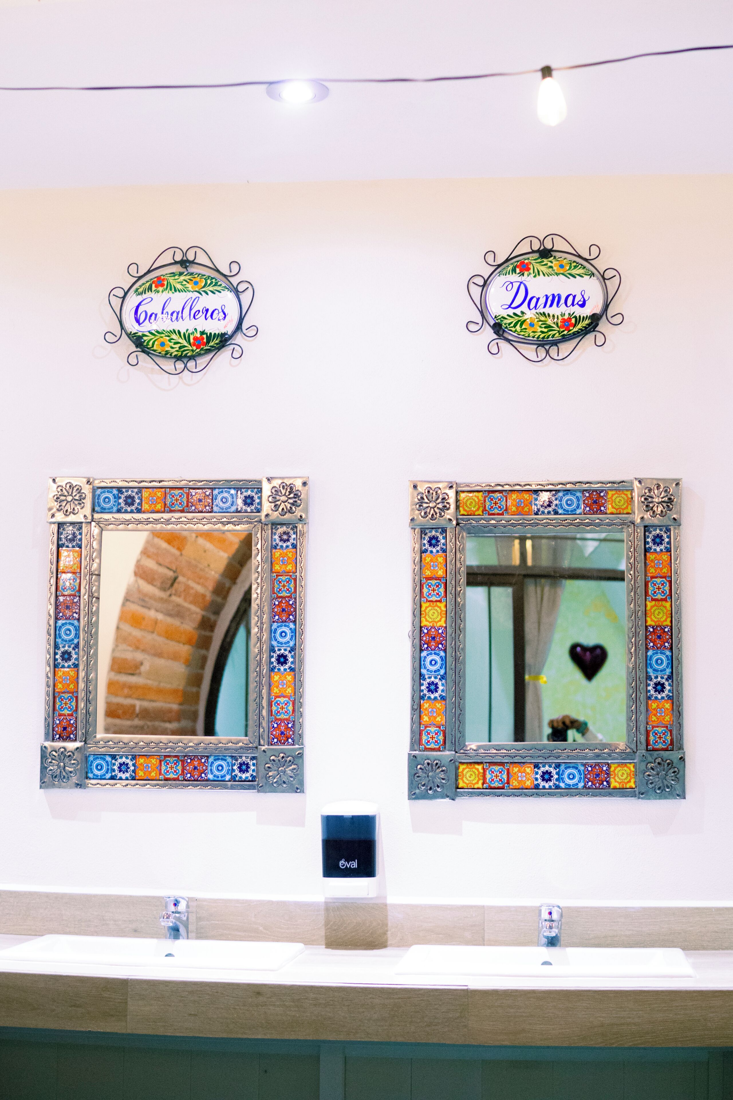 Two bathroom mirrors with decorative frames, a sink, and a light fixture above.