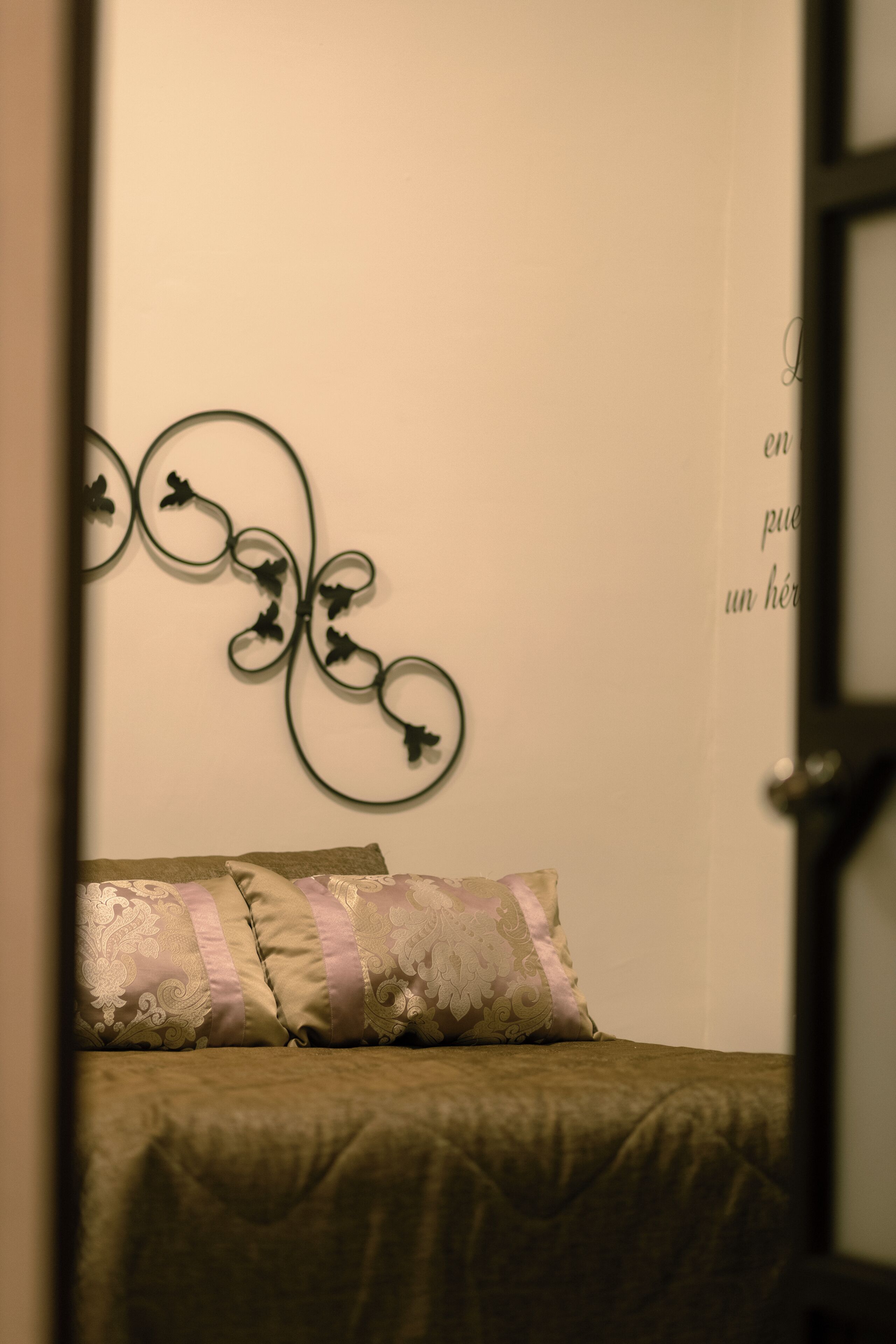 A bedroom with a bed, decorative wall art, and a partial view of a door.