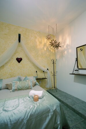 A bedroom with a bed, a heart-shaped decoration, a star-shaped hanging light, and a mirror on the wall.