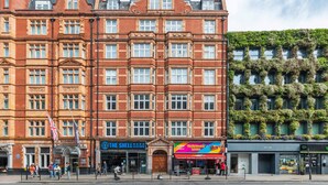 A red brick building with multiple windows and a green wall with plants. - Chic Spacious Holborn Apartment (London)