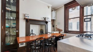 A kitchen with a wooden table, chairs, a built-in stove, and a window with a view of the outside. - Chic Spacious Holborn Apartment (London)