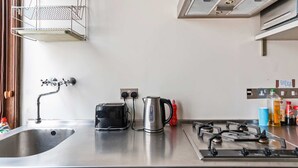 A kitchen with a stainless steel sink, a toaster, a kettle, a gas stove, and various kitchen items on the counter. - Chic Spacious Holborn Apartment (London)