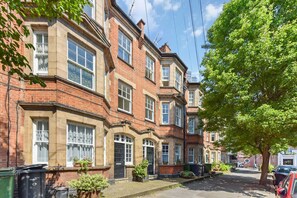 A row of terraced houses with brick facades, windows, and a tree on the right. - Spacious Duplex 3 bed on the Southbank (London)
