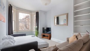 Une chambre moderne avec un grand lit, un canapé, une télévision et un miroir.