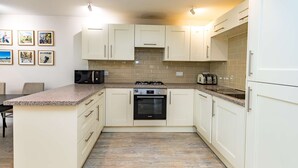 A kitchen with white cabinets, a granite countertop, a built-in oven, and a microwave. - Beautiful Earlsfield Home With Garden (London)