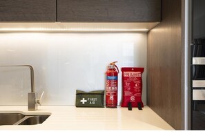 A kitchen with a stainless steel sink, a fire extinguisher, a first aid kit, and a fire blanket. - Stunning 1 bed Apartment Kings Cross St Pancras (London)
