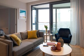 A modern living room with a sofa, a round coffee table, a side table, and a chair. - Stunning 1 bed Apartment Kings Cross St Pancras (London)