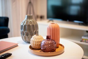Three decorative vases on a white table in a room with a TV and a black chair in the background. - Stunning 1 bed Apartment Kings Cross St Pancras (London)