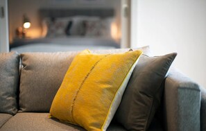 Un sofá gris con un cojín amarillo y uno marrón.