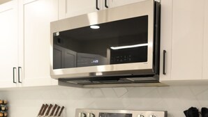 Una cocina con electrodomésticos de acero inoxidable, armarios blancos y un juego de cuchillos.