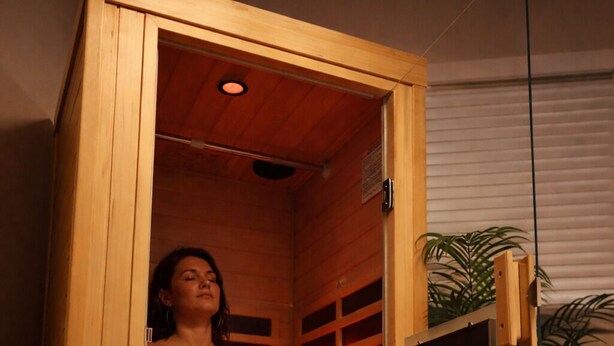 Una sauna con interior de madera, un banco y una planta.