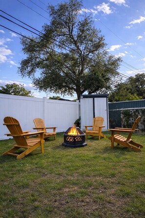 A backyard with a fire pit, wooden Adirondack chairs, and a white fence. - Luxury Wellness Retreat -Infrared Sauna · Massage Chair · Red Light Therapy (Seminole)